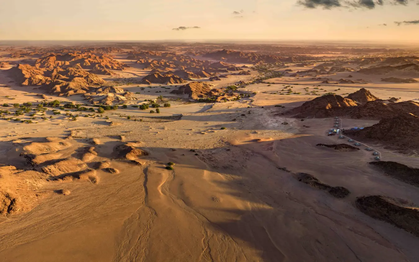 Aerial view of desert landscape with scattered rock formations and safari vehicle, Hoanib Elephant Camp, Skeleton Coast, Namibia