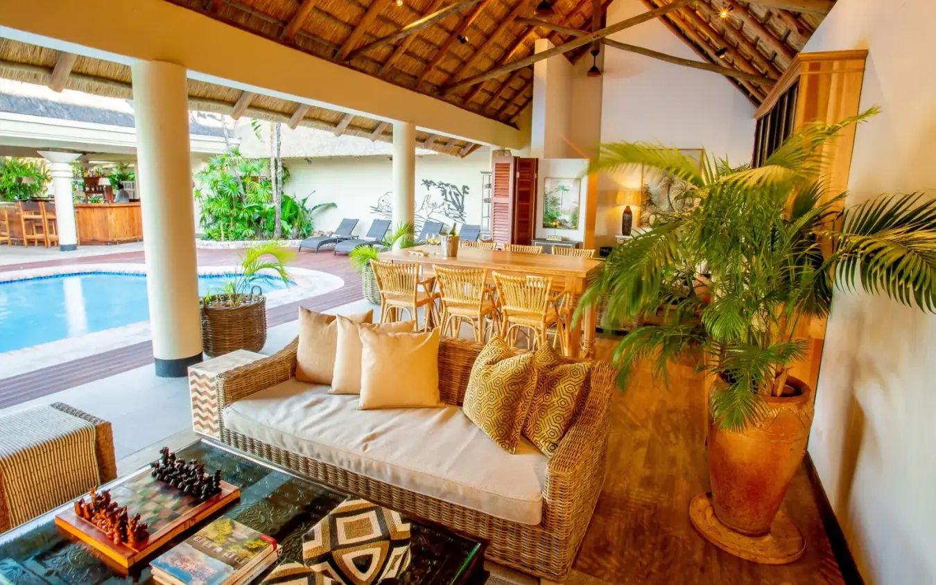 Luxury lounge with woven furniture and pool view through open colonnade, Ilala Lodge Hotel, Victoria Falls, Zimbabwe