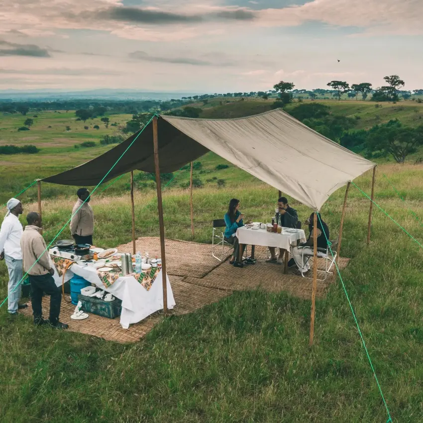 Safari camp dining setup under canvas in grassland landscape, Ishasha Wilderness Camp, Queen Elizabeth NP, Uganda