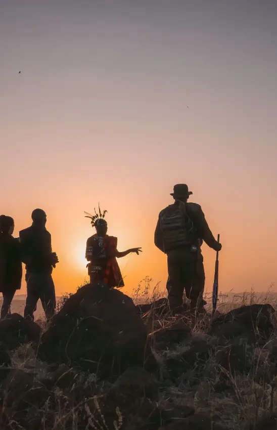 Group of hikers silhouetted against sunset on grassland savanna, Kifaru House, Laikipia Highlands, Kenya