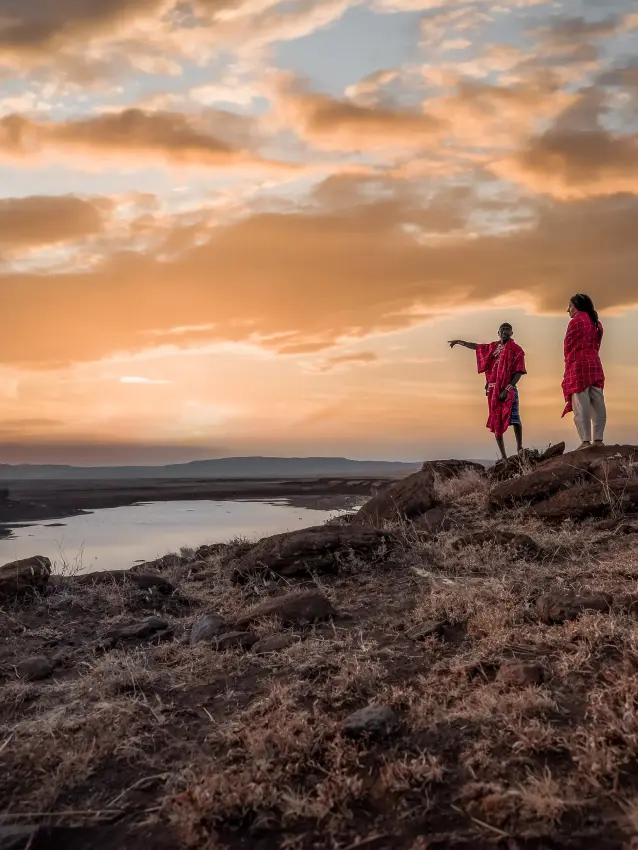 Two Maasai warriors standing on hilltop overlooking valley at sunset, Kifaru House, Laikipia Highlands, Kenya