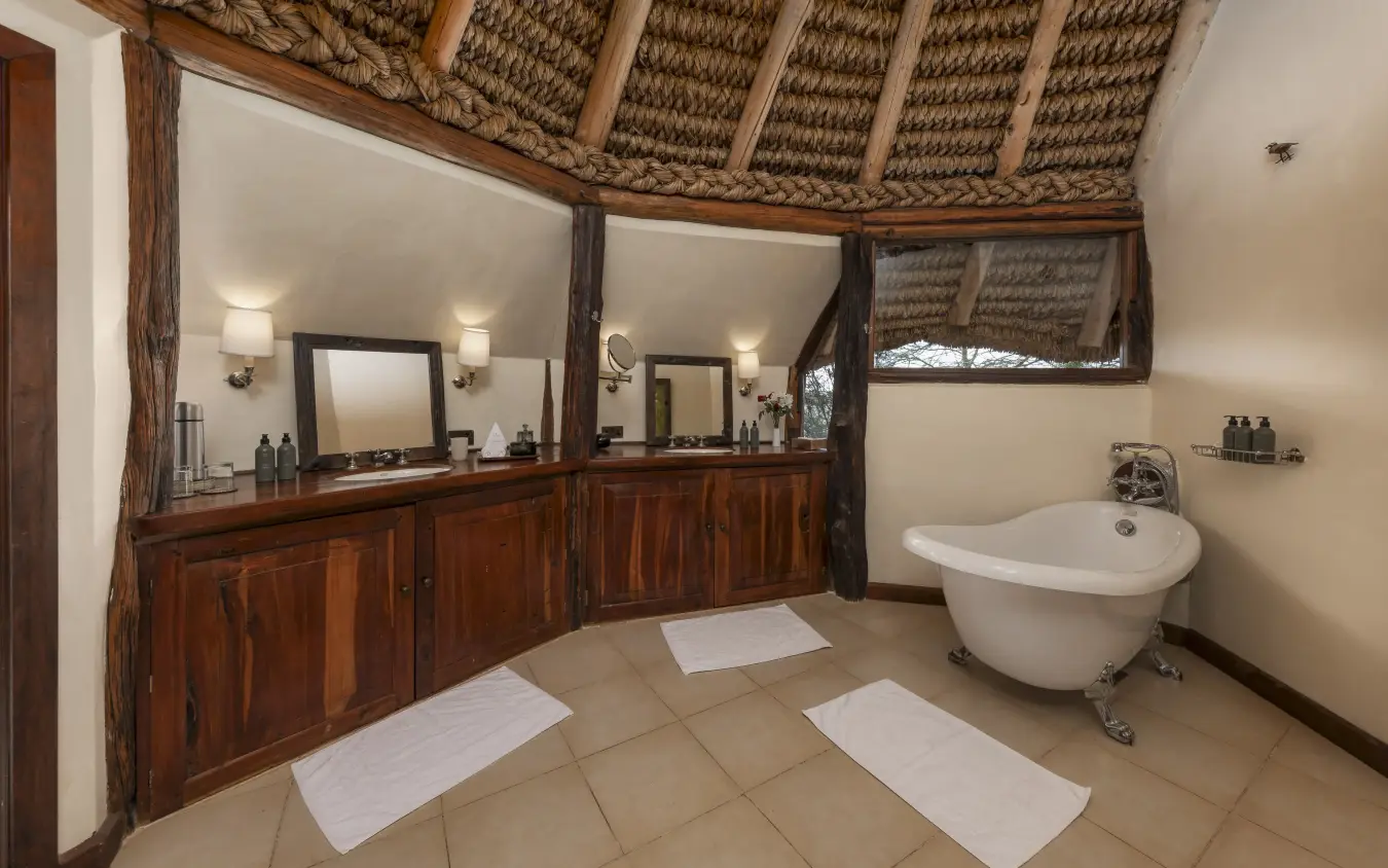 Luxury bathroom with wooden vanity and freestanding bathtub under thatched roof, Kifaru House, Laikipia Highlands, Kenya