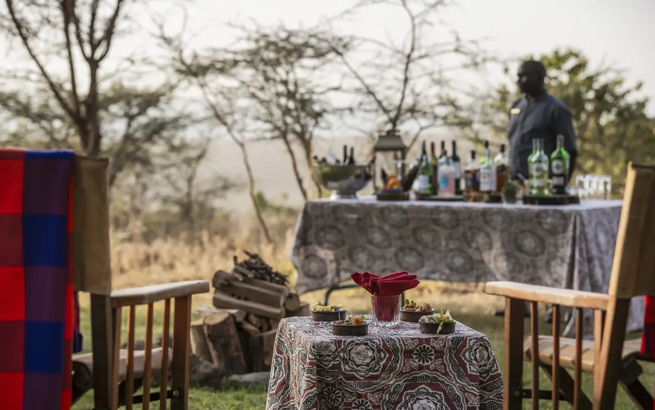 Outdoor dining setup with bar table overlooking savanna landscape, Kifaru House, Laikipia Highlands, Kenya