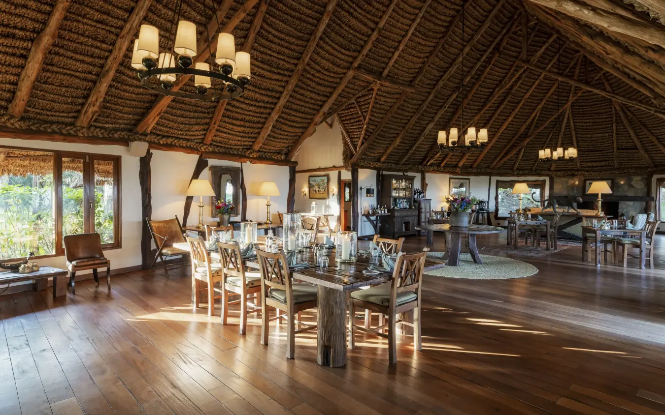 Open-plan lodge interior with wooden beams and thatched ceiling overlooking savanna, Kifaru House, Laikipia Highlands, Kenya