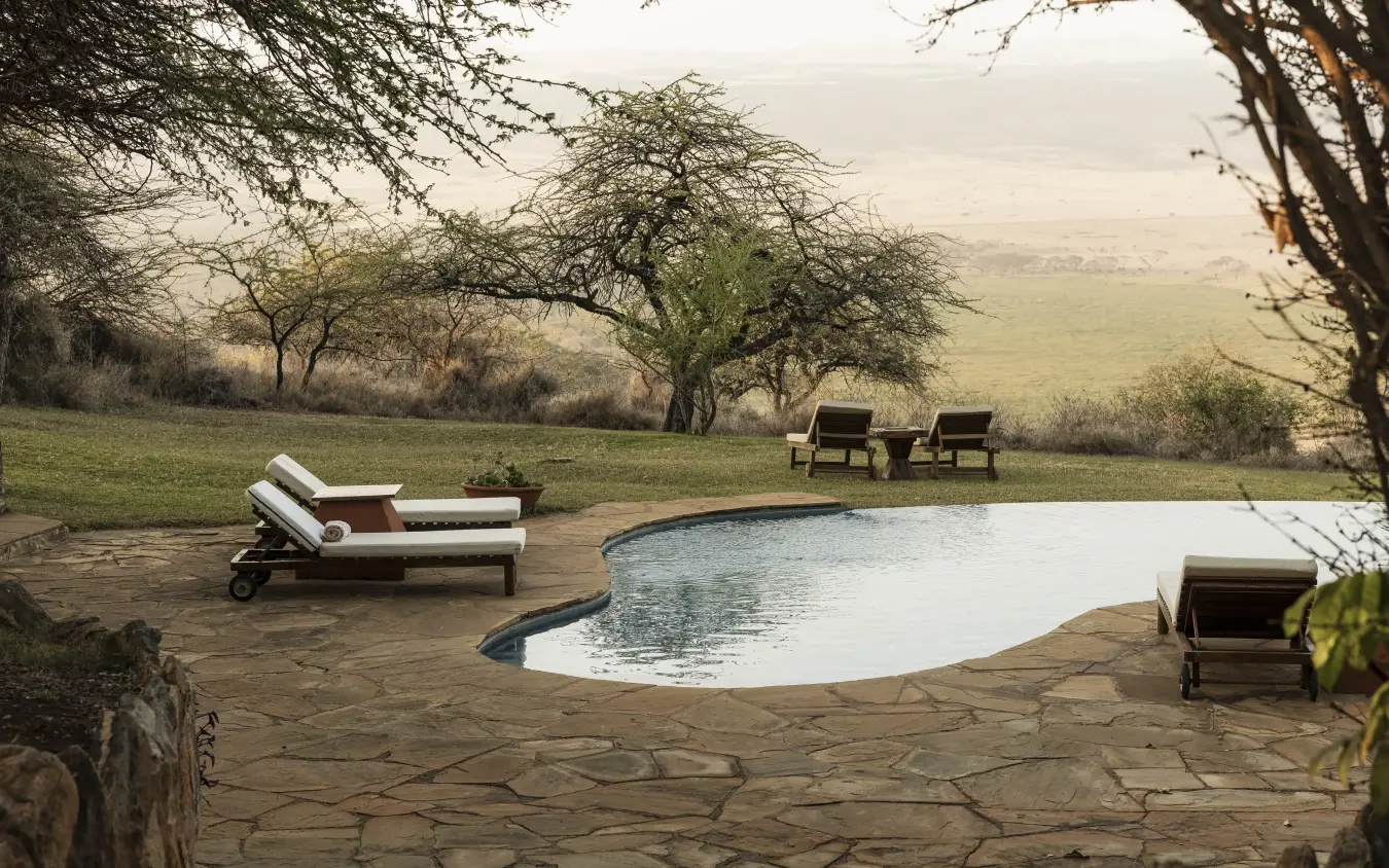 Infinity pool with loungers overlooking savanna landscape at dusk, Kifaru House, Laikipia Highlands, Kenya