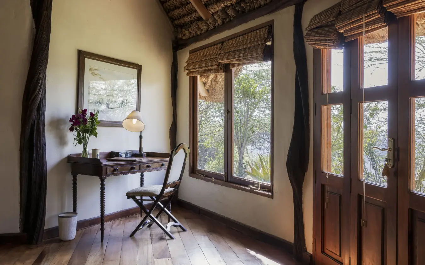 Desk and chair in safari lodge room with large windows overlooking trees, Kifaru House, Laikipia Highlands, Kenya