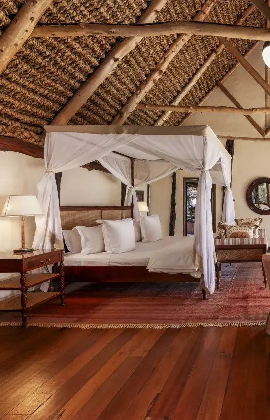 Four-poster canopy bed in thatched-roof safari lodge bedroom, Kifaru House, Laikipia Highlands, Kenya