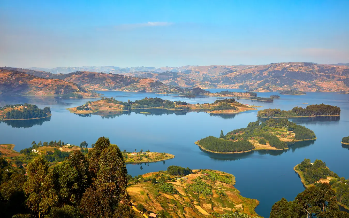 Aerial view of forested islands dotting blue lake with mountains