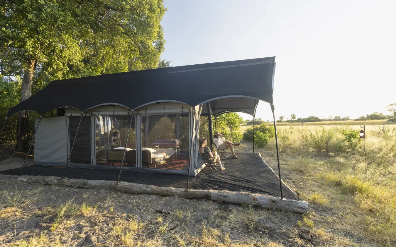Canvas safari tent with extended awning in savanna landscape