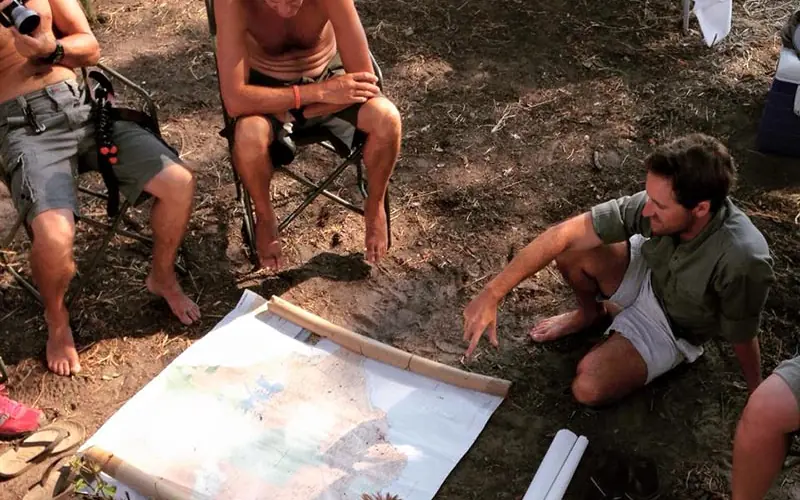 Group reviewing map on ground during outdoor camping activity