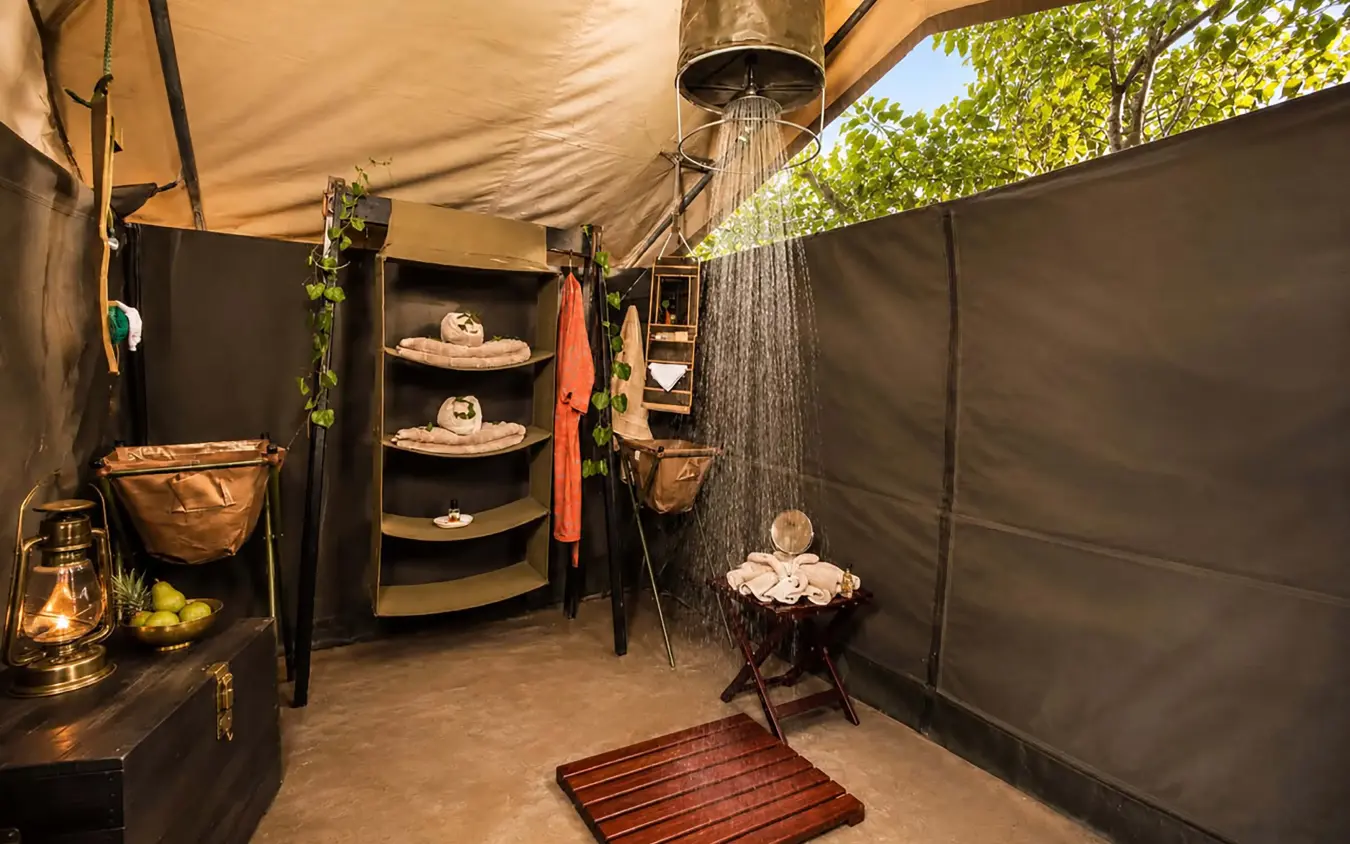 Outdoor shower enclosure with rainfall showerhead and safari-style furnishings