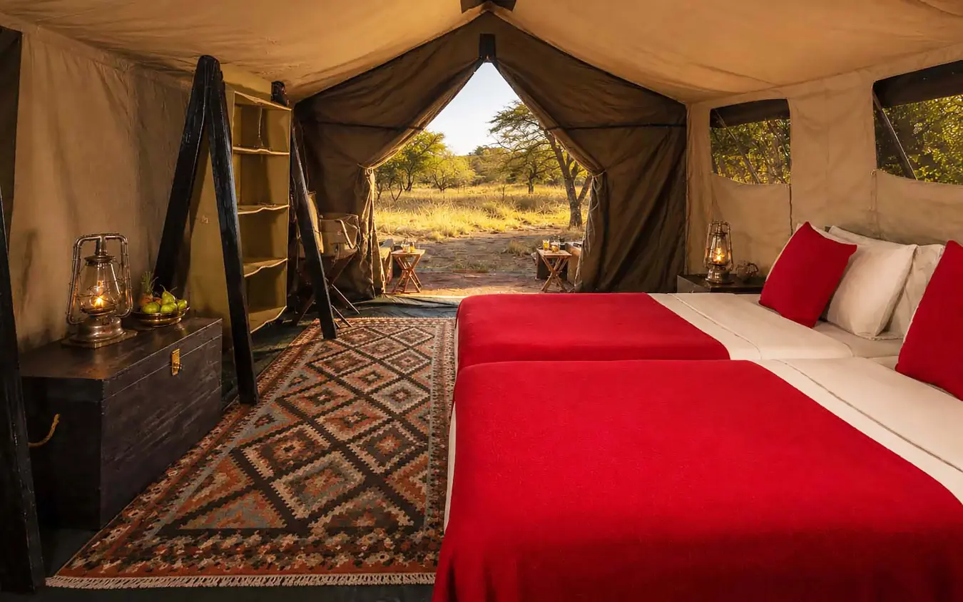 Luxury safari tent interior with four-poster bed overlooking African savanna