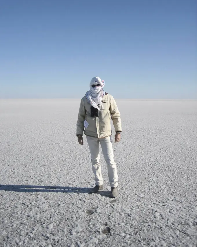 Guest walking across vast white salt pan landscape, San Camp, Makgadikgadi Pans, Botswana