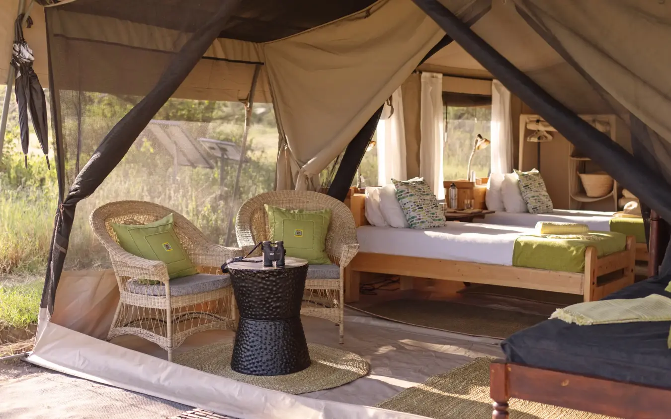 Luxury safari tent interior with sitting area and bed overlooking grassland, Serengeti North Wilderness Camp, Serengeti National Park, Tanzania