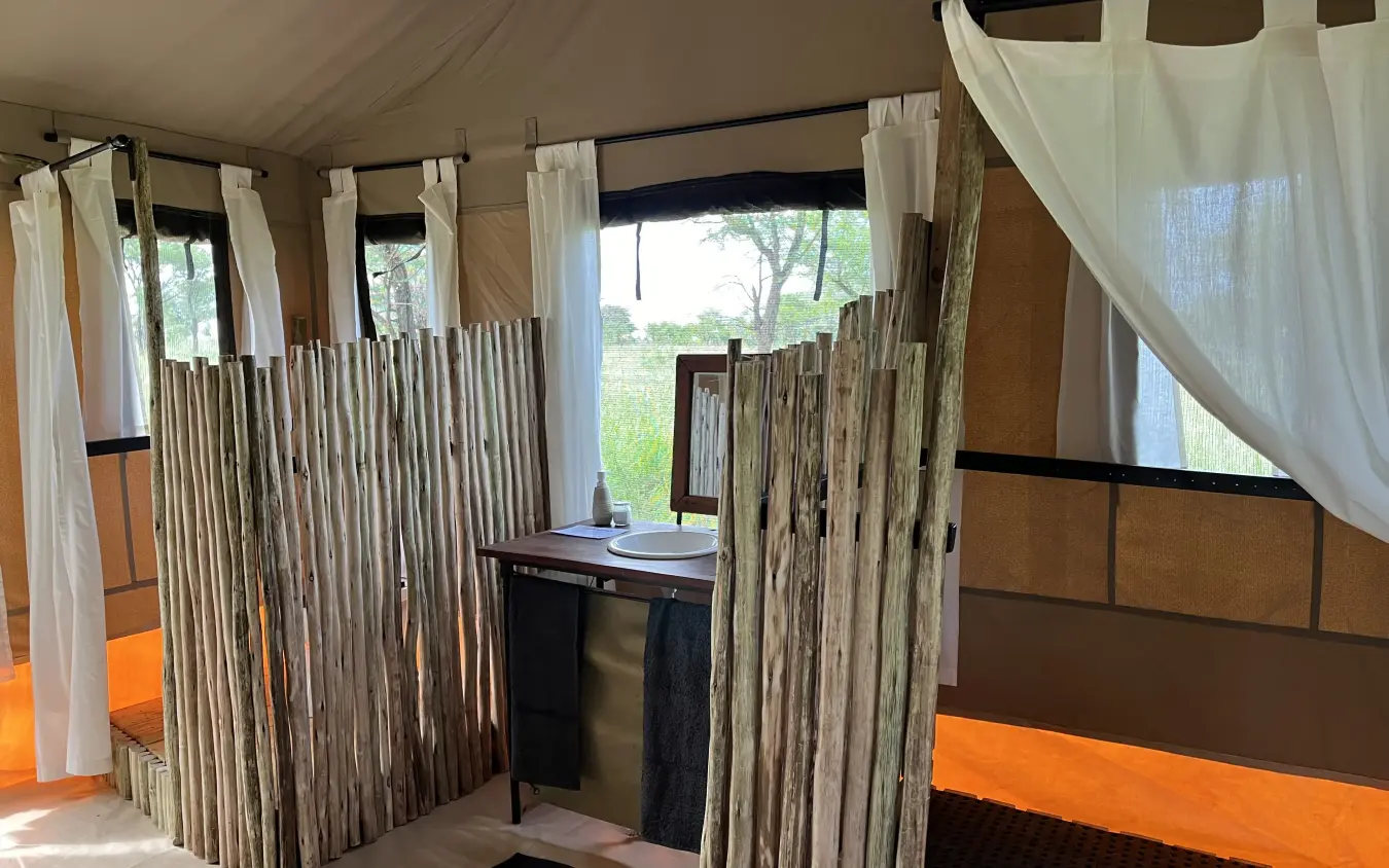 Luxury safari tent bedroom with wooden privacy screens and savanna views, Serengeti Wilderness Camp, Serengeti National Park, Tanzania