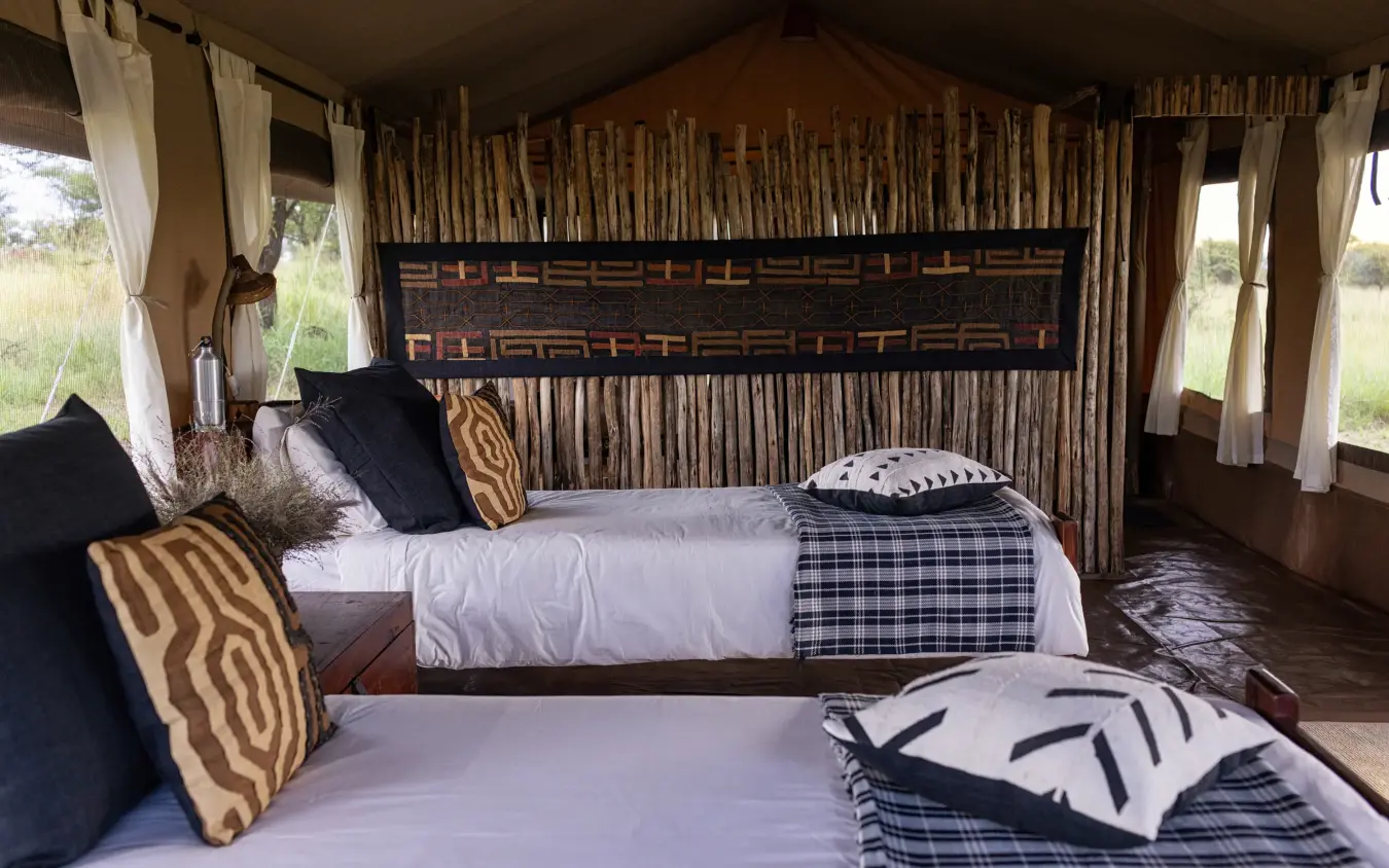 Luxury safari tent bedroom with twin beds and natural wood furnishings, Serengeti Wilderness Camp, Serengeti National Park, Tanzania
