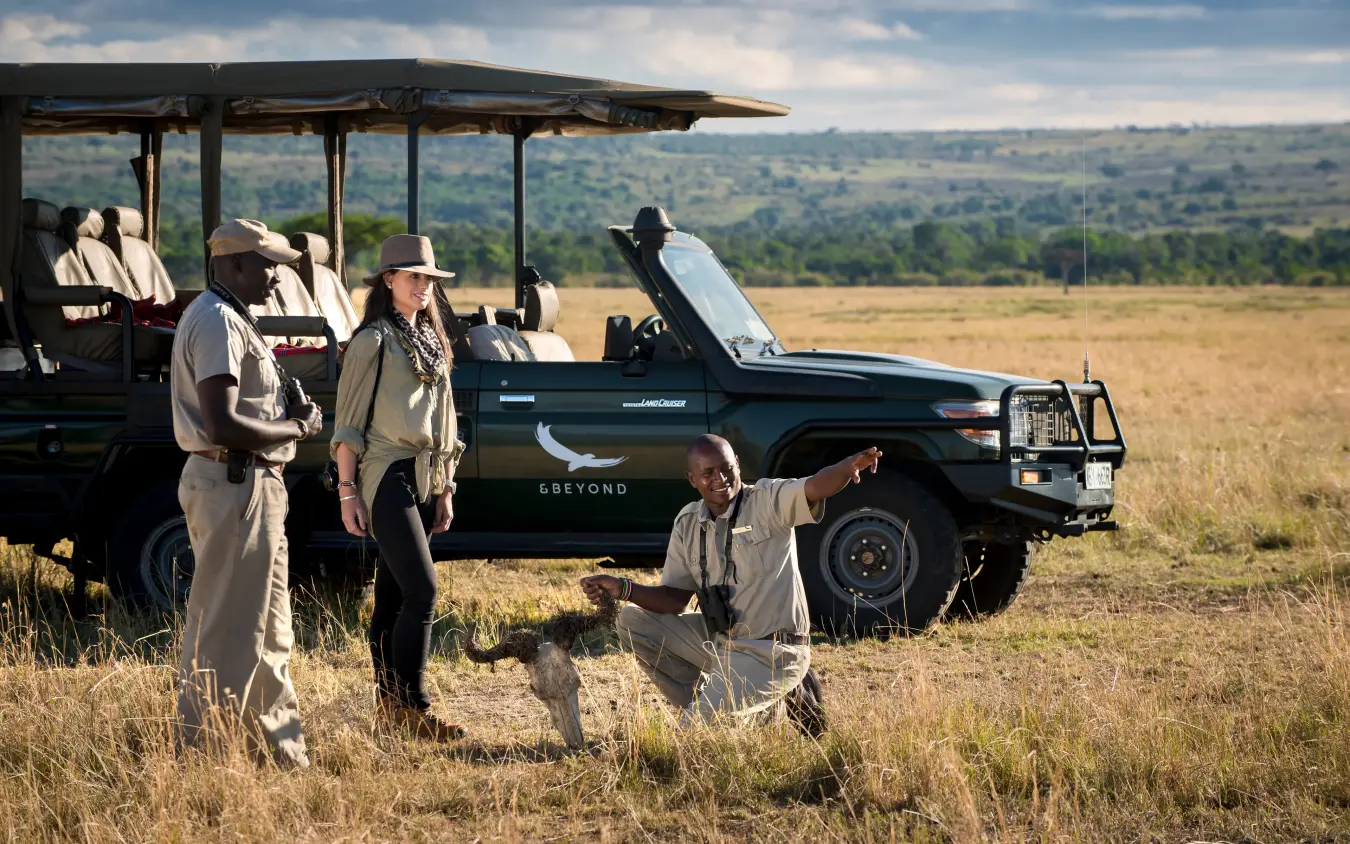 Safari guide pointing out wildlife to guests near open-top vehicle, Suyian Lodge, Laikipia Highlands, Kenya