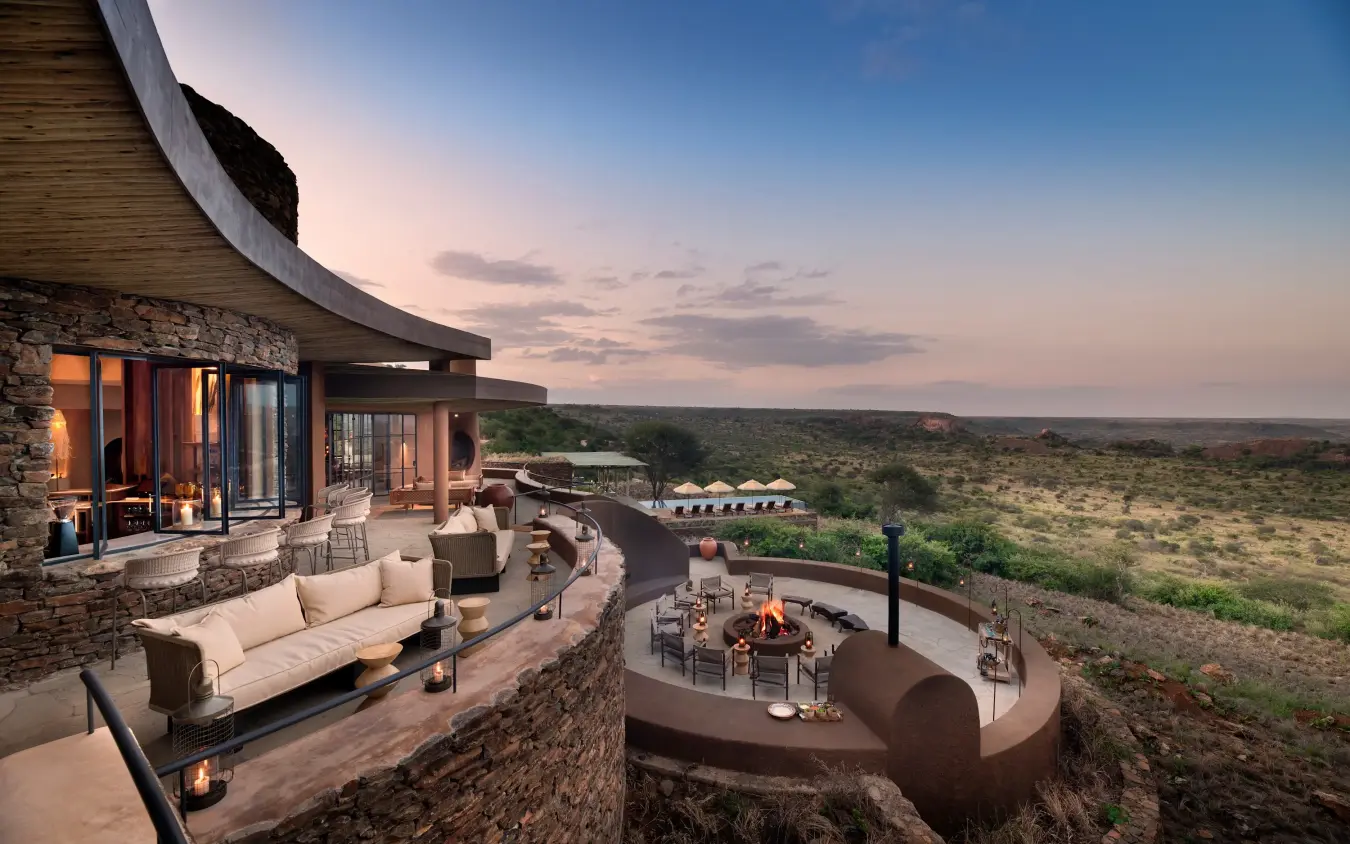 Luxury lodge terrace with firepit overlooking vast savanna landscape at dusk, Suyian Lodge, Laikipia Highlands, Kenya
