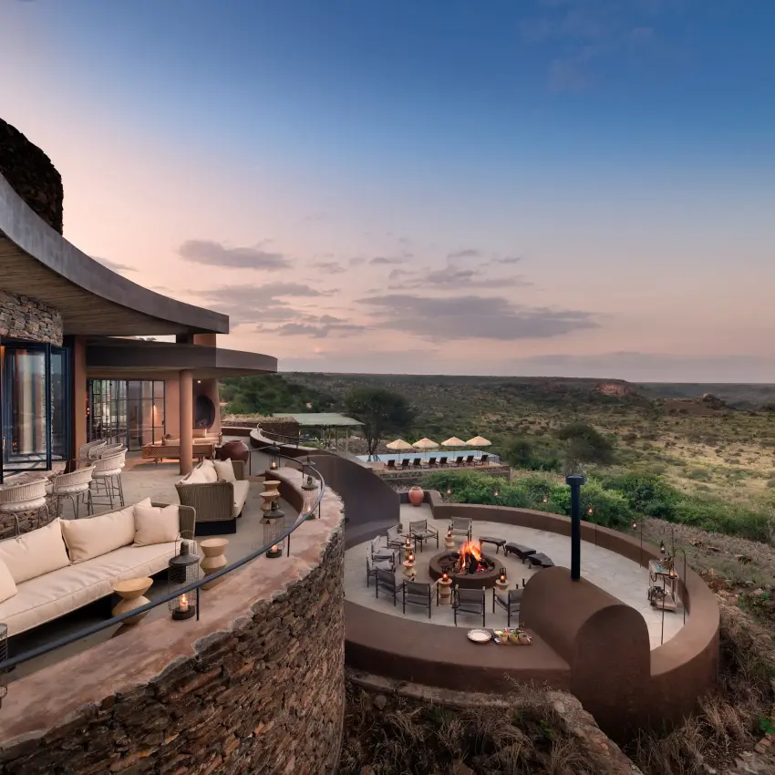 Luxury lodge terrace with firepit overlooking vast savanna landscape at dusk, Suyian Lodge, Laikipia Highlands, Kenya