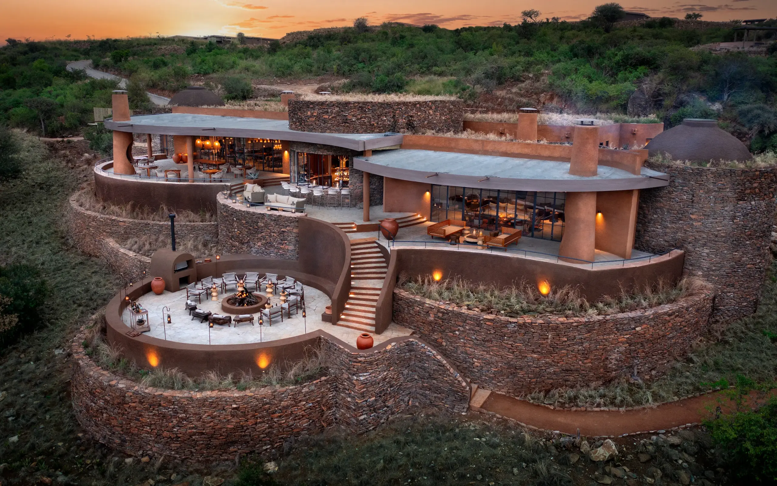 Luxury lodge with curved stone walls nestled into hillside at dusk, Suyian Lodge, Laikipia Highlands, Kenya