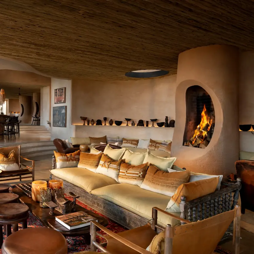 Luxury lodge interior with fireplace, lounge seating and earth-tone decor, Suyian Lodge, Laikipia Highlands, Kenya