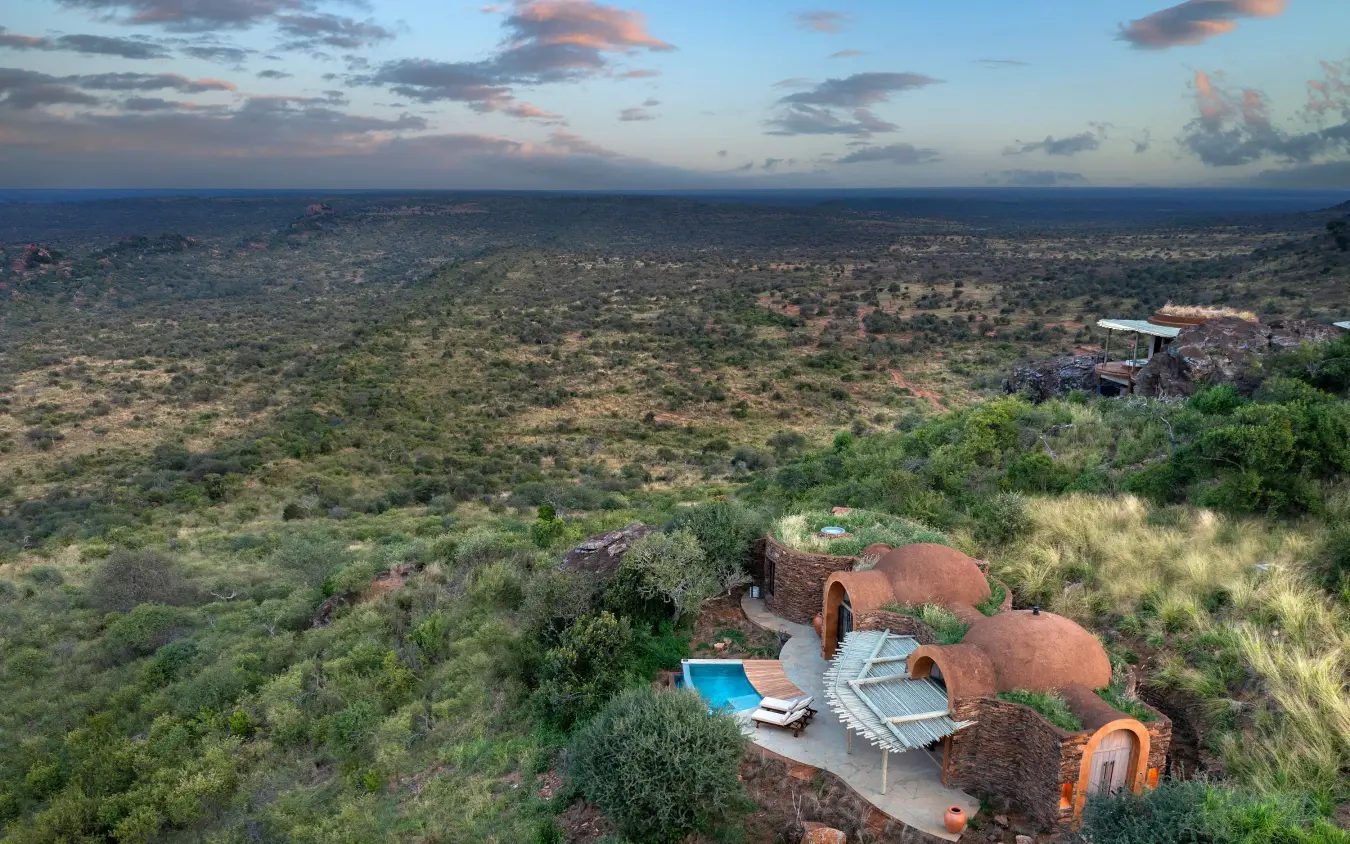 Dome-shaped lodge structures with pools overlooking vast savanna landscape at dusk, Suyian Lodge, Laikipia Highlands, Kenya