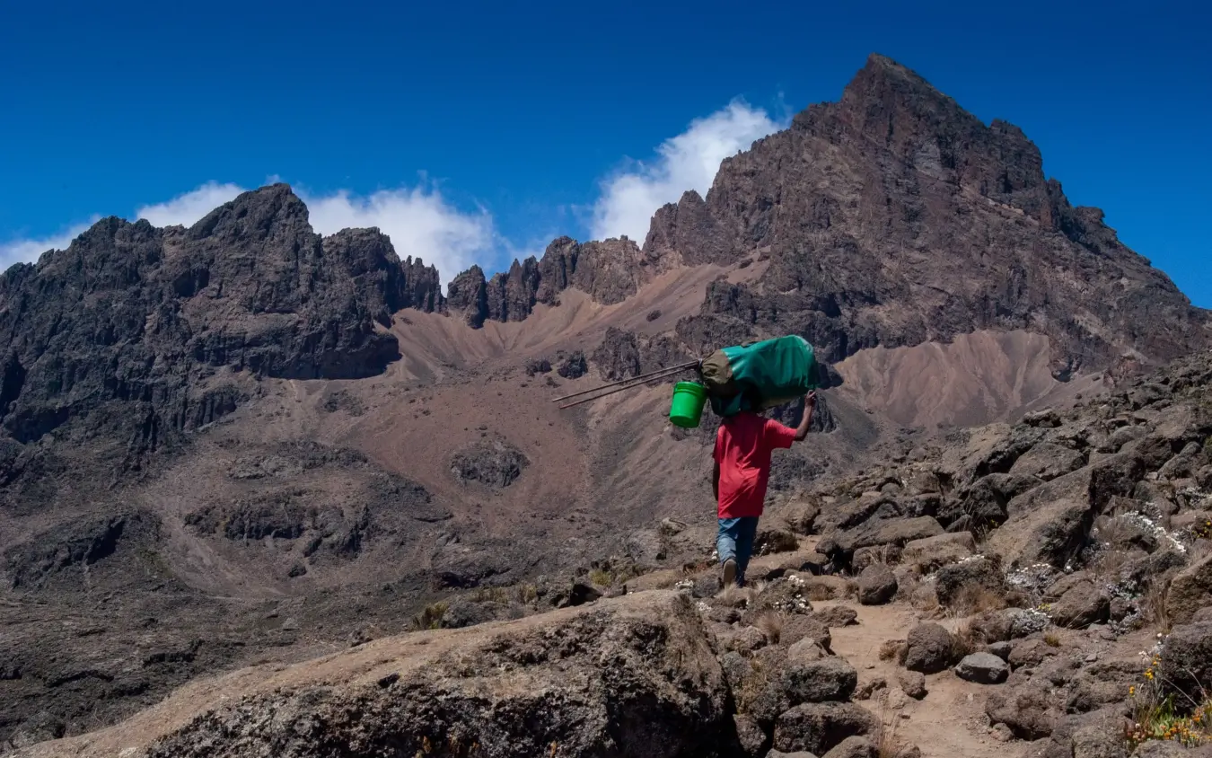 Porter carrying supplies along rocky trail on Mount Kilimanjaro Tanzania