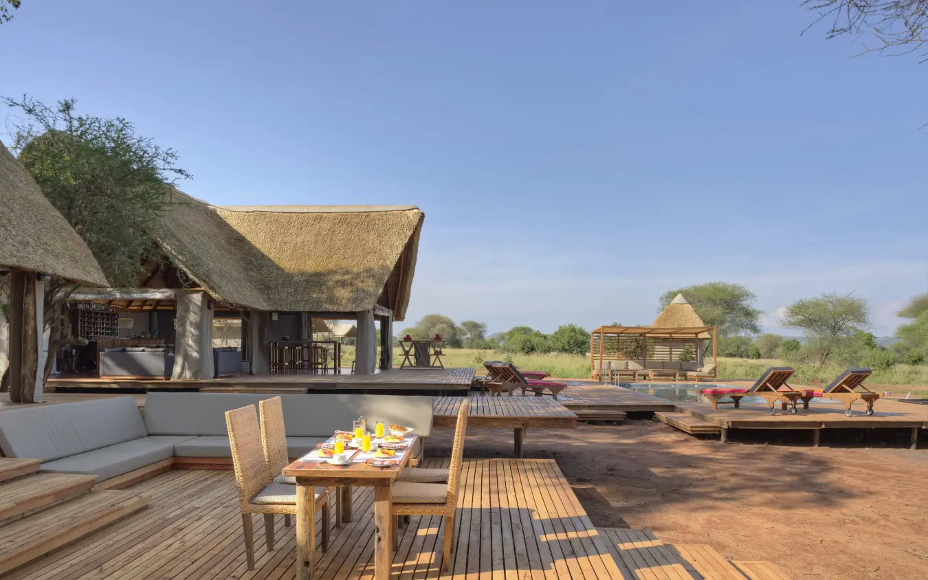 Luxury safari lodge deck with thatched-roof structures overlooking savanna plains, Tarangire Ndovu Tented Lodge, Tarangire National Park, Tanzania