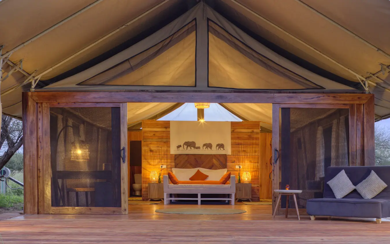 Luxury safari tent with open wooden doors and illuminated interior at dusk, Tarangire Ndovu Tented Lodge, Tarangire National Park, Tanzania
