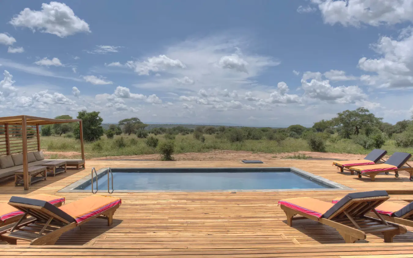 Swimming pool with loungers overlooking savanna landscape at midday, Tarangire Ndovu Tented Lodge, Tarangire National Park, Tanzania