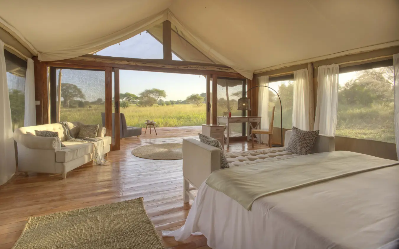 Luxury safari tent interior with bed and lounge area overlooking grassland, Tarangire Ndovu Tented Lodge, Tarangire National Park, Tanzania