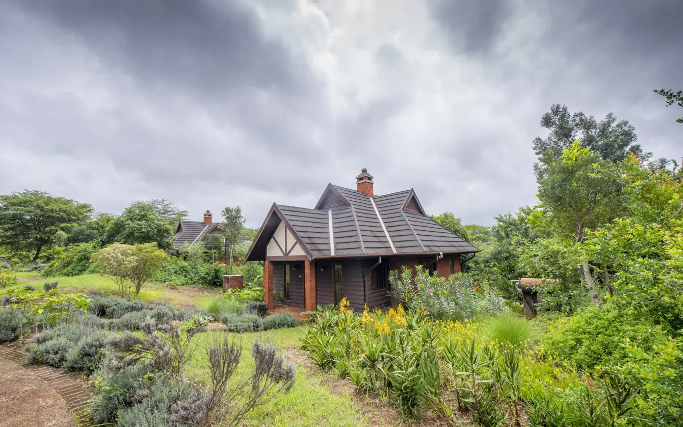 Luxury lodge with thatched roof nestled in lush garden landscape, The Retreat at Ngorongoro, Ngorongoro Crater, Tanzania