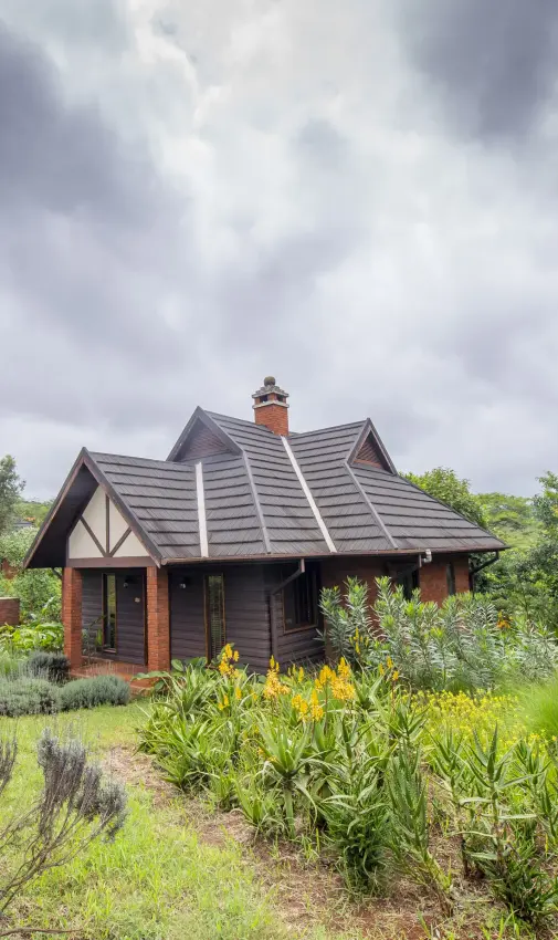 Thatched-roof lodge surrounded by indigenous gardens and woodland vegetation, The Retreat at Ngorongoro, Ngorongoro Crater, Tanzania