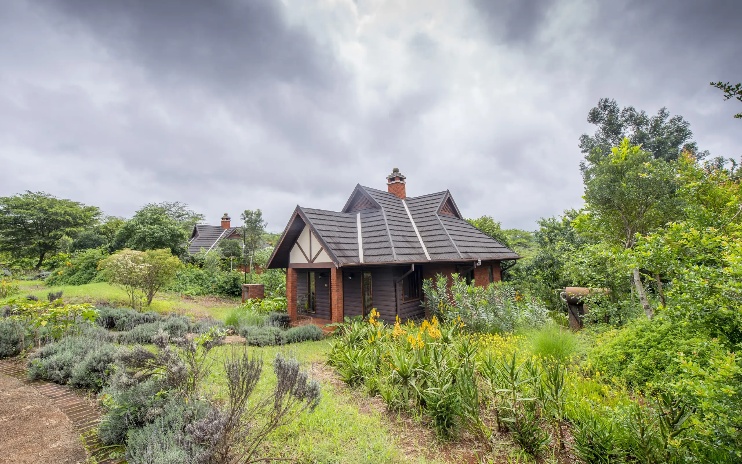 Thatched-roof lodge surrounded by indigenous gardens and woodland vegetation, The Retreat at Ngorongoro, Ngorongoro Crater, Tanzania