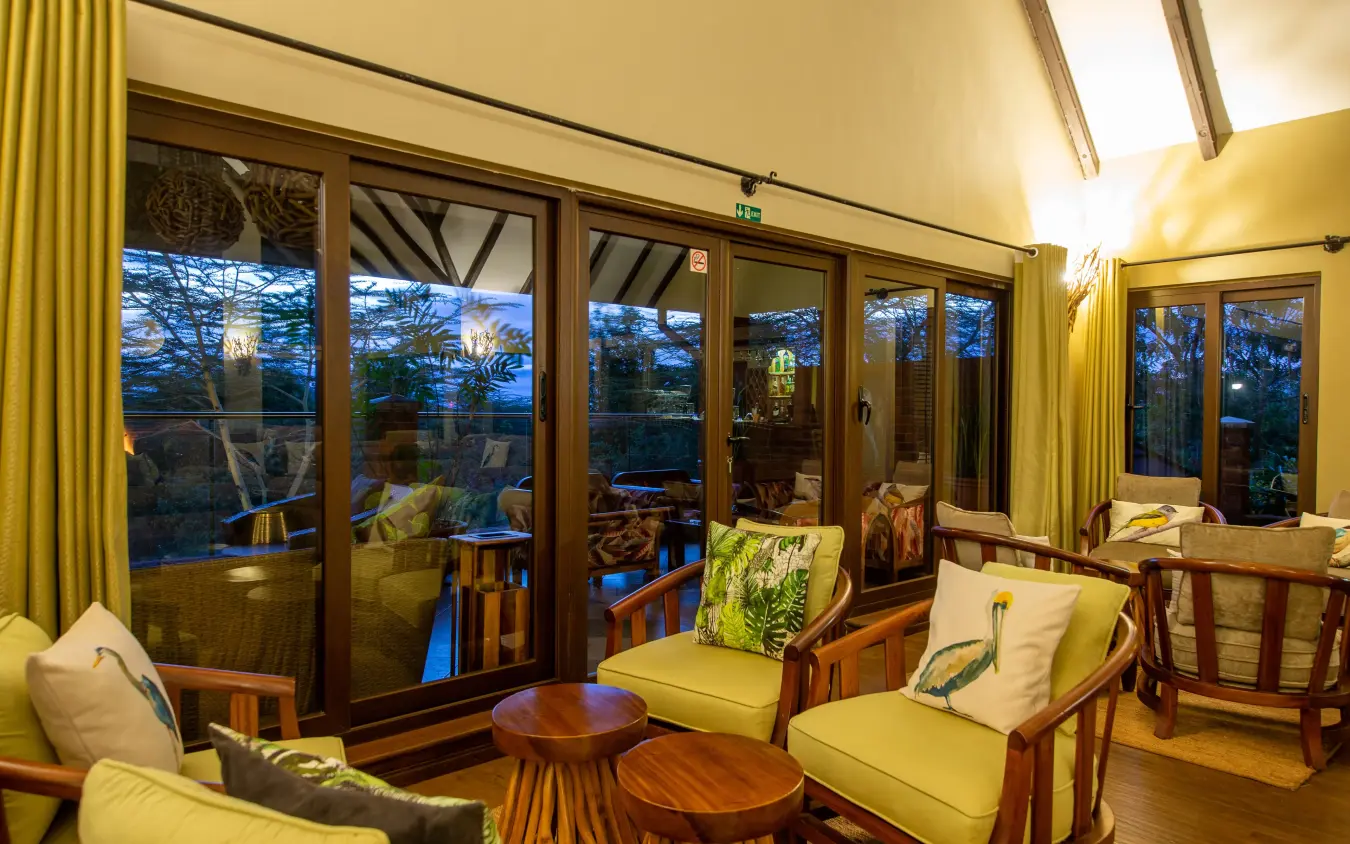 Luxury lounge with floor-to-ceiling windows overlooking twilight landscape, The Retreat at Ngorongoro, Ngorongoro Crater, Tanzania