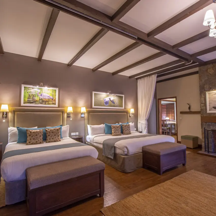 Luxury bedroom suite with fireplace and dual beds, The Retreat at Ngorongoro, Ngorongoro Crater, Tanzania