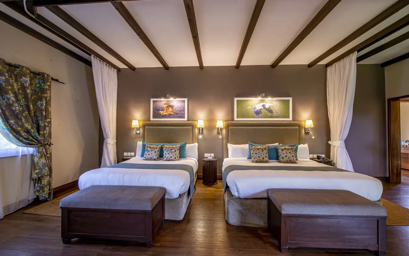 Luxury twin bedroom with exposed beam ceiling and framed wildlife artwork, The Retreat at Ngorongoro, Ngorongoro Crater, Tanzania