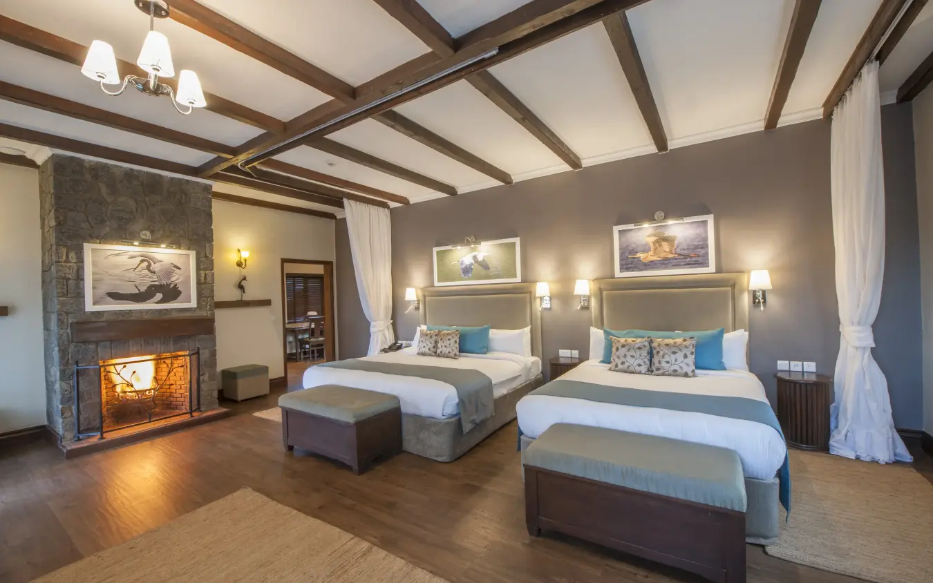 Luxury bedroom suite with fireplace and dual beds under exposed beam ceiling, The Retreat at Ngorongoro, Ngorongoro Crater, Tanzania