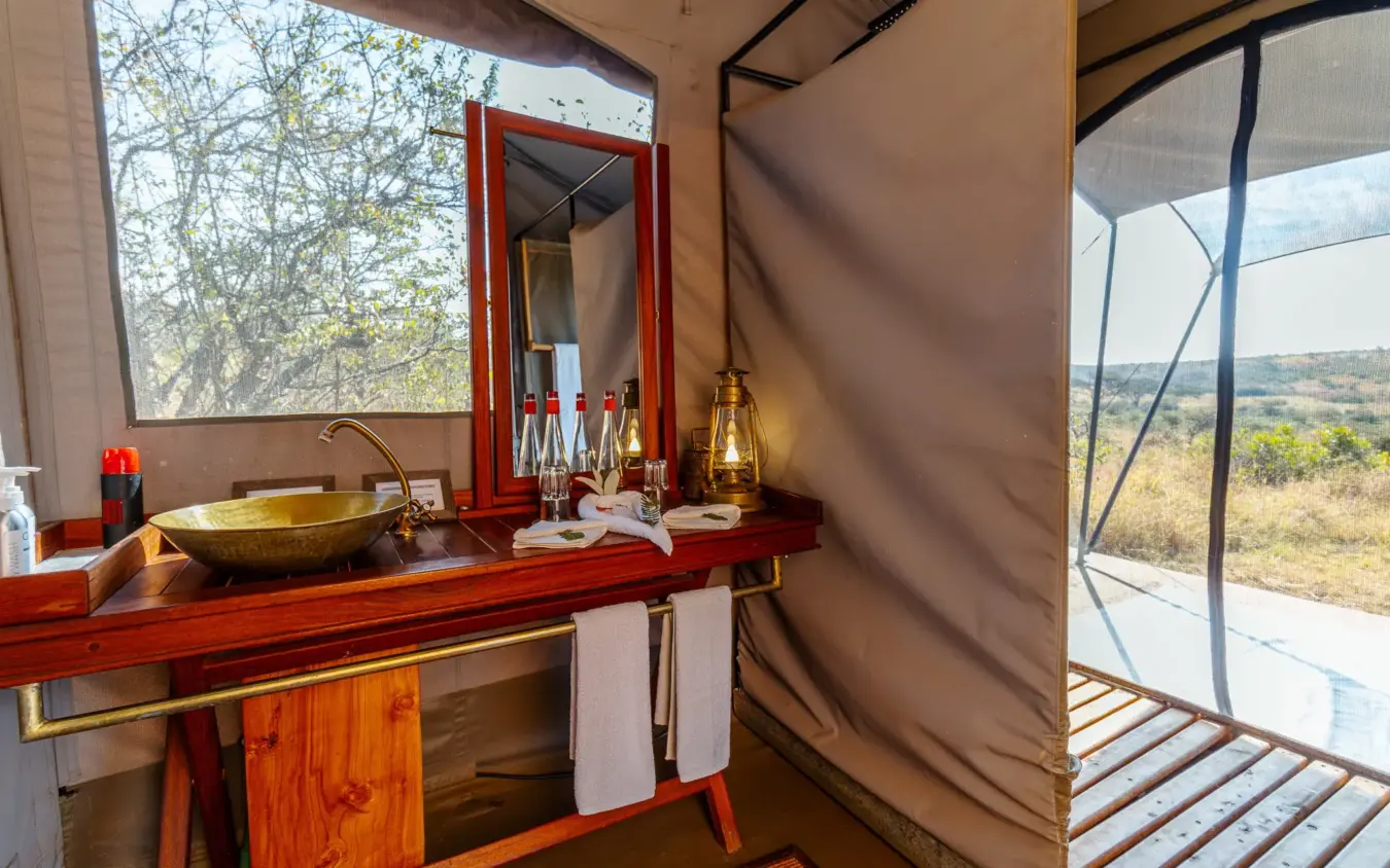 Luxury safari tent bathroom with brass basin and savanna views, Basecamp Wilderness, Maasai Mara, Kenya