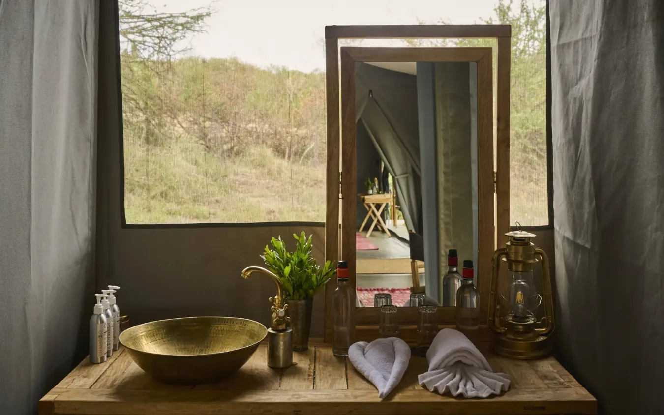 Luxury bathroom sink with mirror overlooking wooded hillside landscape, Basecamp Wilderness, Maasai Mara, Kenya