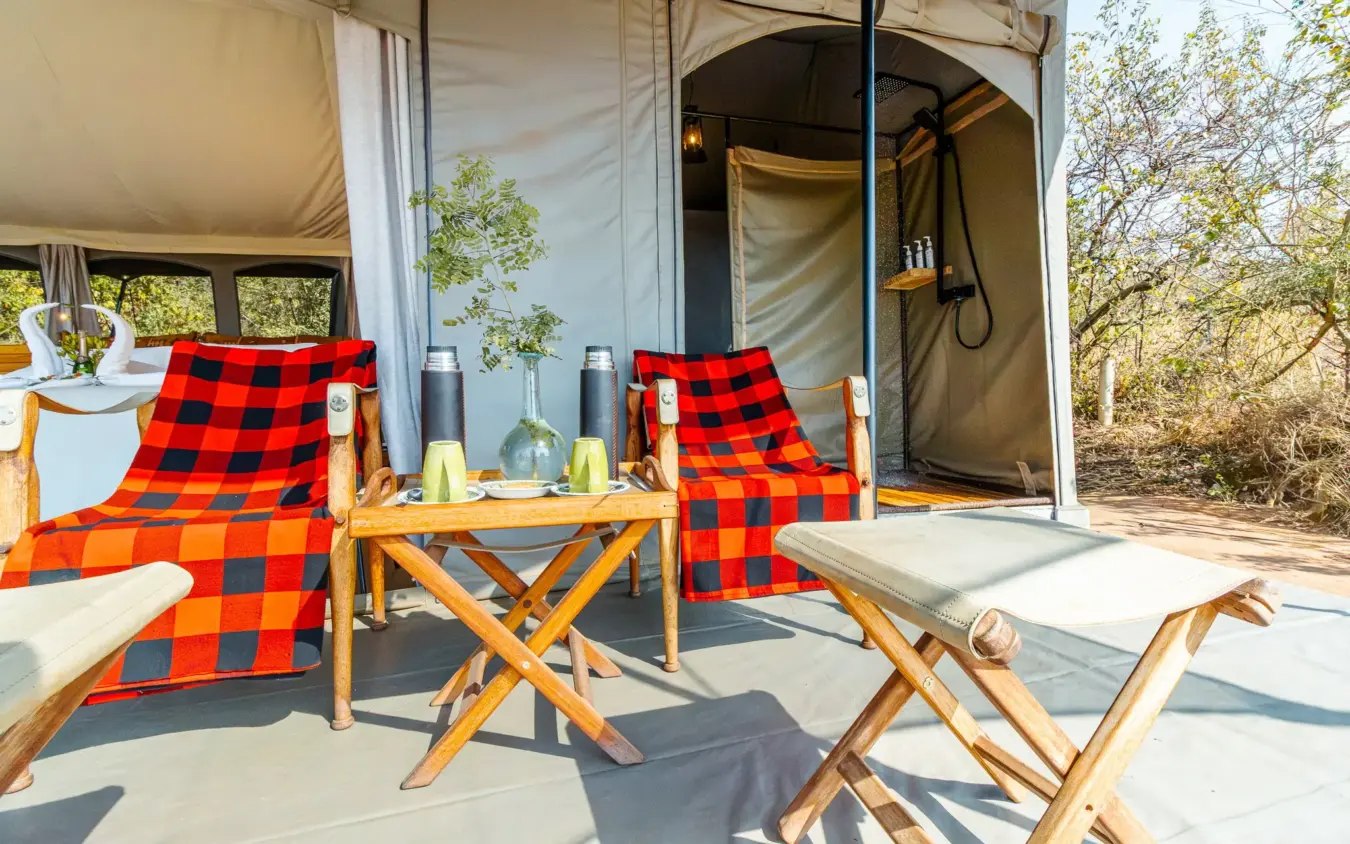 Glamping tent with red checked chairs and outdoor deck area, Basecamp Wilderness, Maasai Mara, Kenya