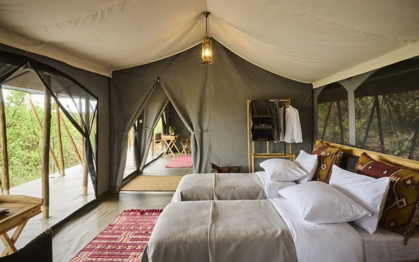 Luxury safari tent interior with dual beds and open views to woodland, Basecamp Wilderness, Maasai Mara, Kenya