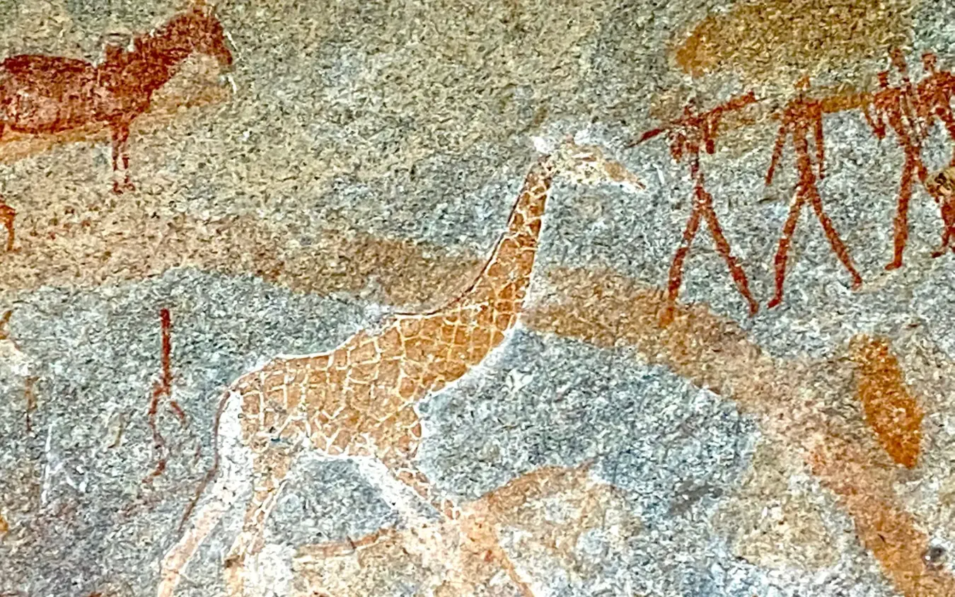 Ancient rock art depicting giraffe and human figures on stone surface, Big Cave Camp, Matobo, Zimbabwe