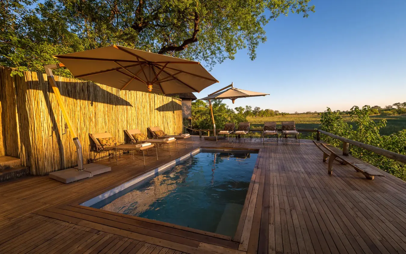 Wooden deck with pool, umbrellas, and savanna views, Savuti Camp, Linyanti Wildlife Reserve, Botswana