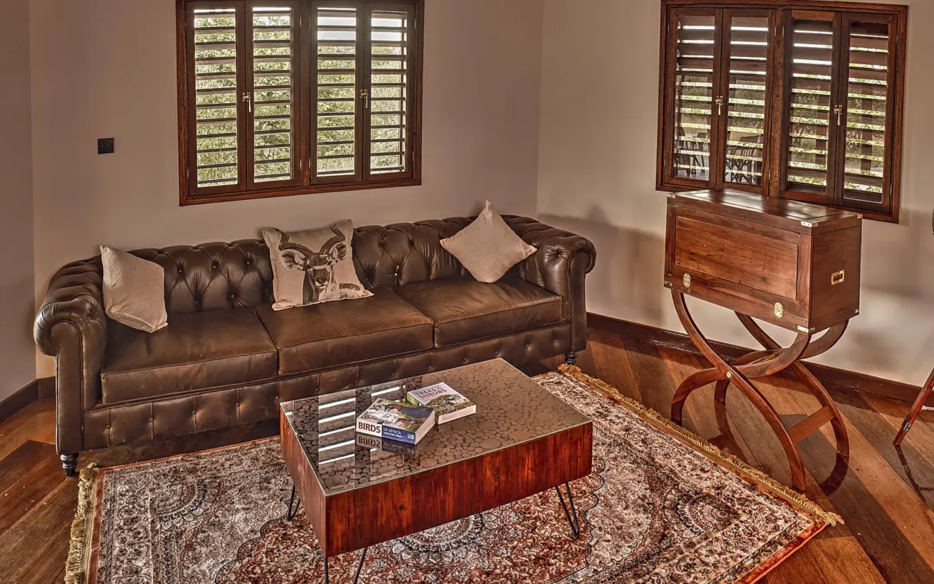 Leather sofa with cushions in wood-paneled lounge room, Deception Valley Lodge, Central Kalahari, Botswana
