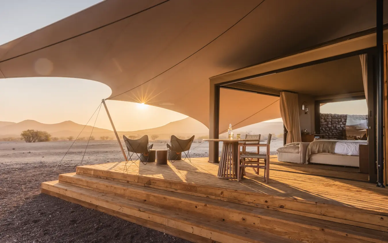 Luxury safari tent with open-air lounge overlooking arid desert landscape at sunset, Desert Rhino Camp, Damaraland, Namibia
