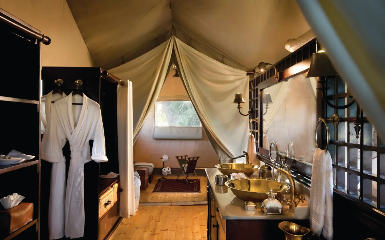Luxury canvas glamping tent interior with brass bathing fixtures and draped fabric, Duba Explorers Camp, The Okavango Delta, Botswana