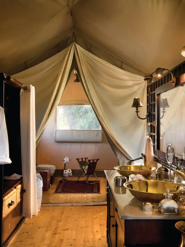Luxury safari tent interior with brass basins and draped cream fabric, Duba Explorers Camp, The Okavango Delta, Botswana