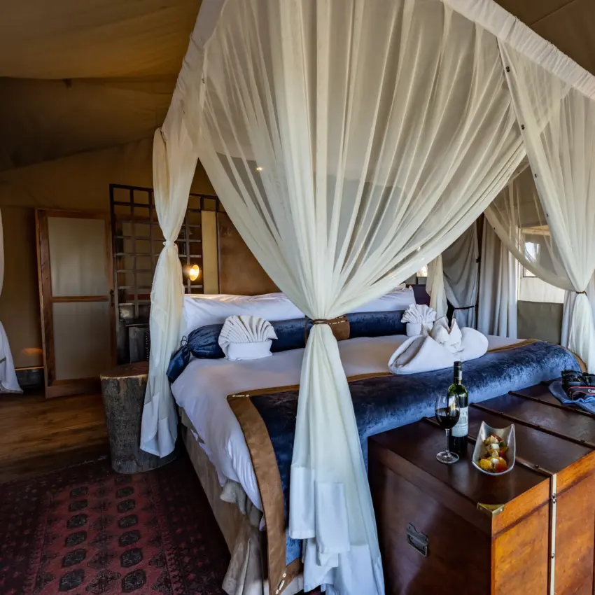 Four-poster bed with white sheer drapes in luxury safari bedroom, Duba Explorers Camp, The Okavango Delta, Botswana