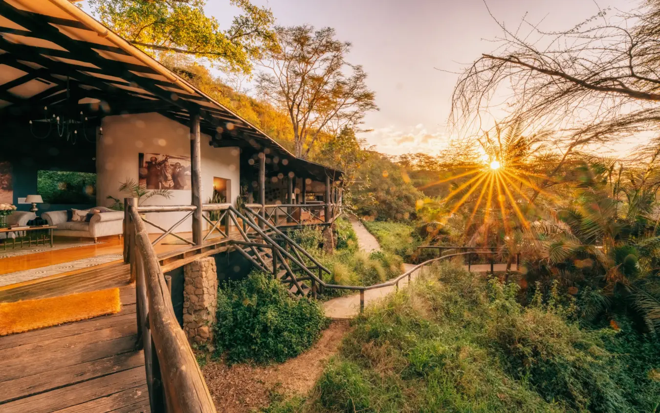 Elevated lodge deck with wooden railings overlooking forested valley at sunset, The Emakoko, Nairobi, Kenya
